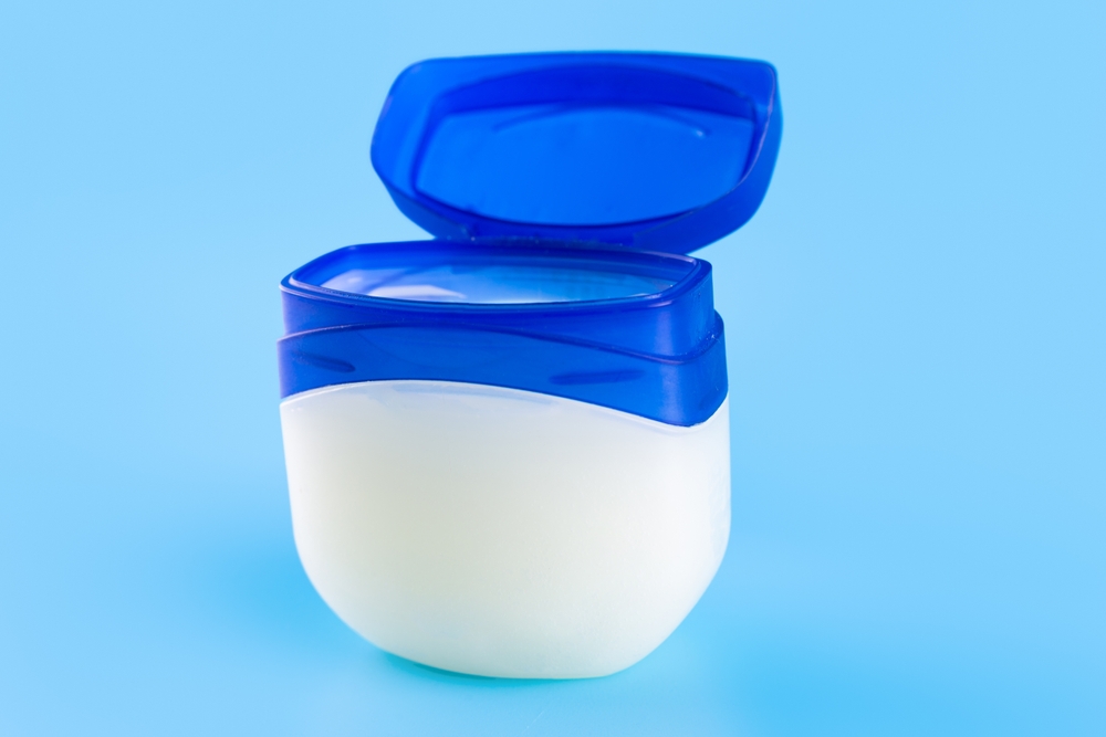 Vaseline or petroleum jelly in a clear jar on blue background